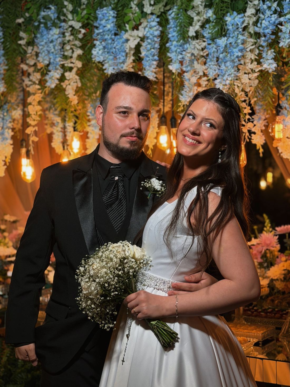 Casal sorrindo com buquê de flores brancas